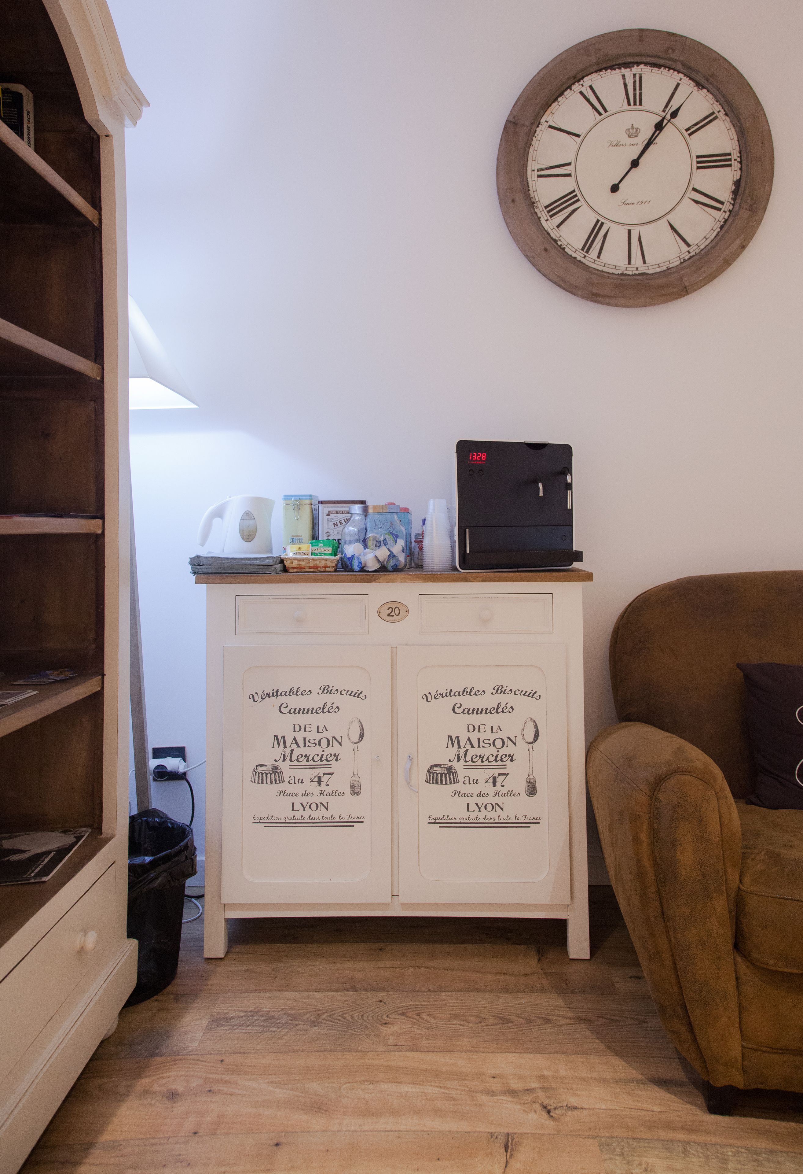 A kitchen with a wooden cabinet, a clock, and a coffee machine.