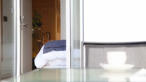 Una habitación de hotel con cama, mesita de noche y separador de vidrio.