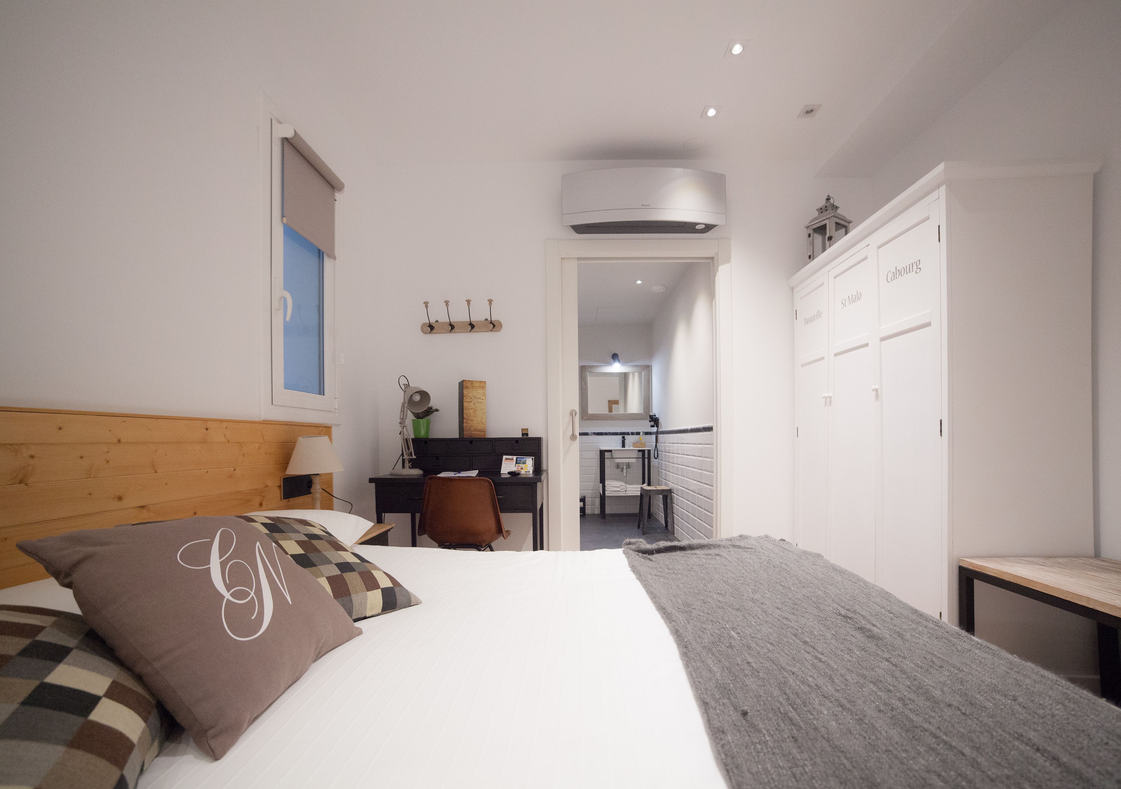 A bedroom with a bed, a desk, and a wardrobe.