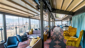 A modern hotel room with large windows, a patterned carpet, and a bar area. - Courtyard by Marriott Sarajevo (Sarajevo)