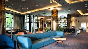 A modern lobby with a blue sofa, seating area, and a bar with shelves. - Courtyard by Marriott Sarajevo (Sarajevo)