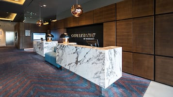 A hotel reception area with a marble counter, modern lighting, and a patterned carpet.