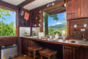 Una cocina rústica con armarios de madera, un lavabo y taburetes.