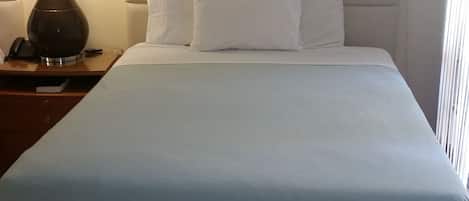 A hotel room with a bed, a nightstand, a lamp, and a telephone.