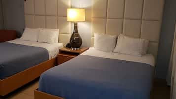 Quarto de hotel com duas camas, uma mesa de cabeceira, um abajur e uma cadeira vermelha.