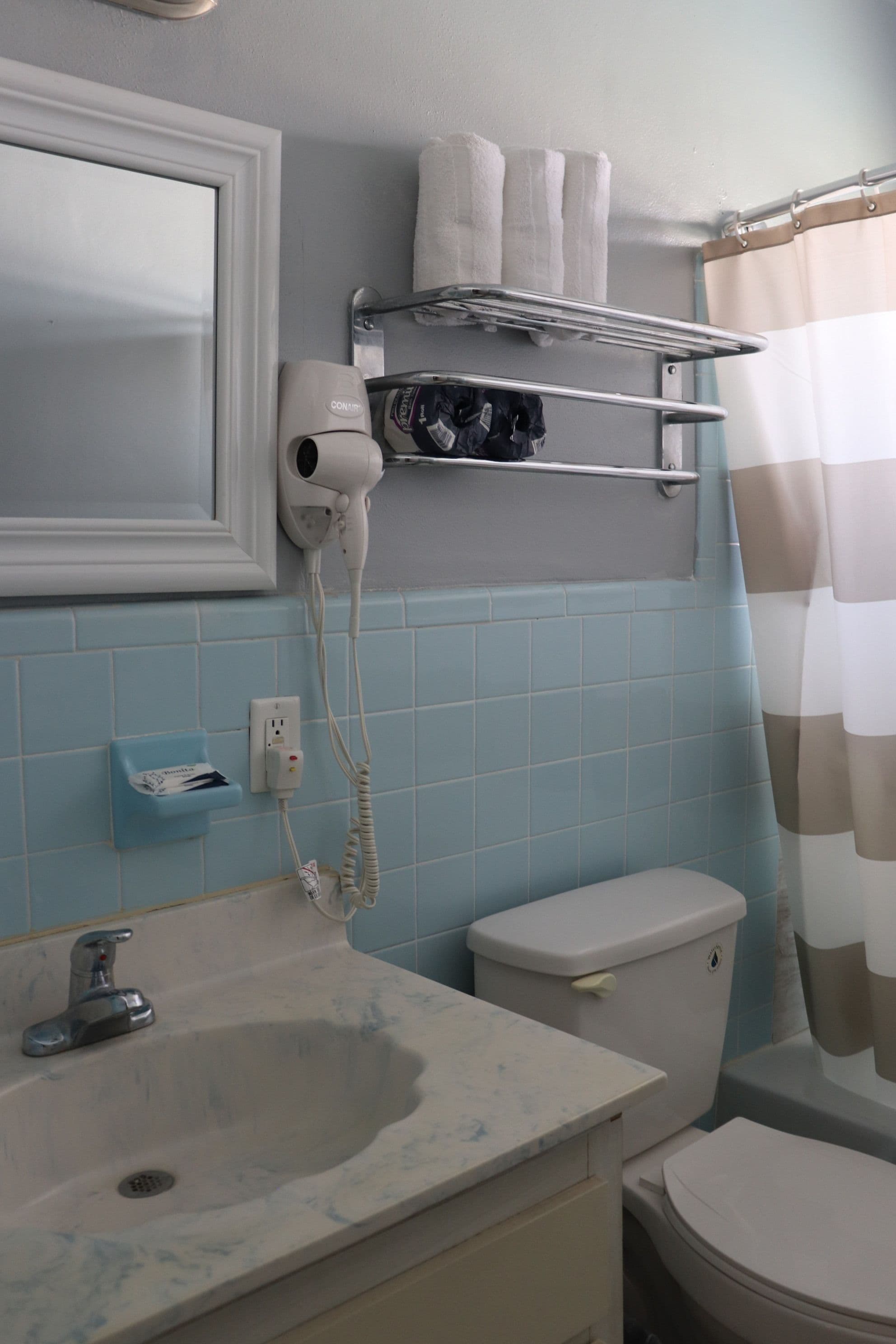 A bathroom with a sink, toilet, and a hairdryer mounted on the wall.