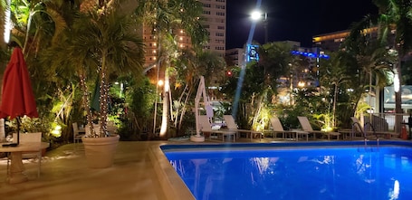 Una piscina al aire libre, sombrillas, sillones reclinables de piscina