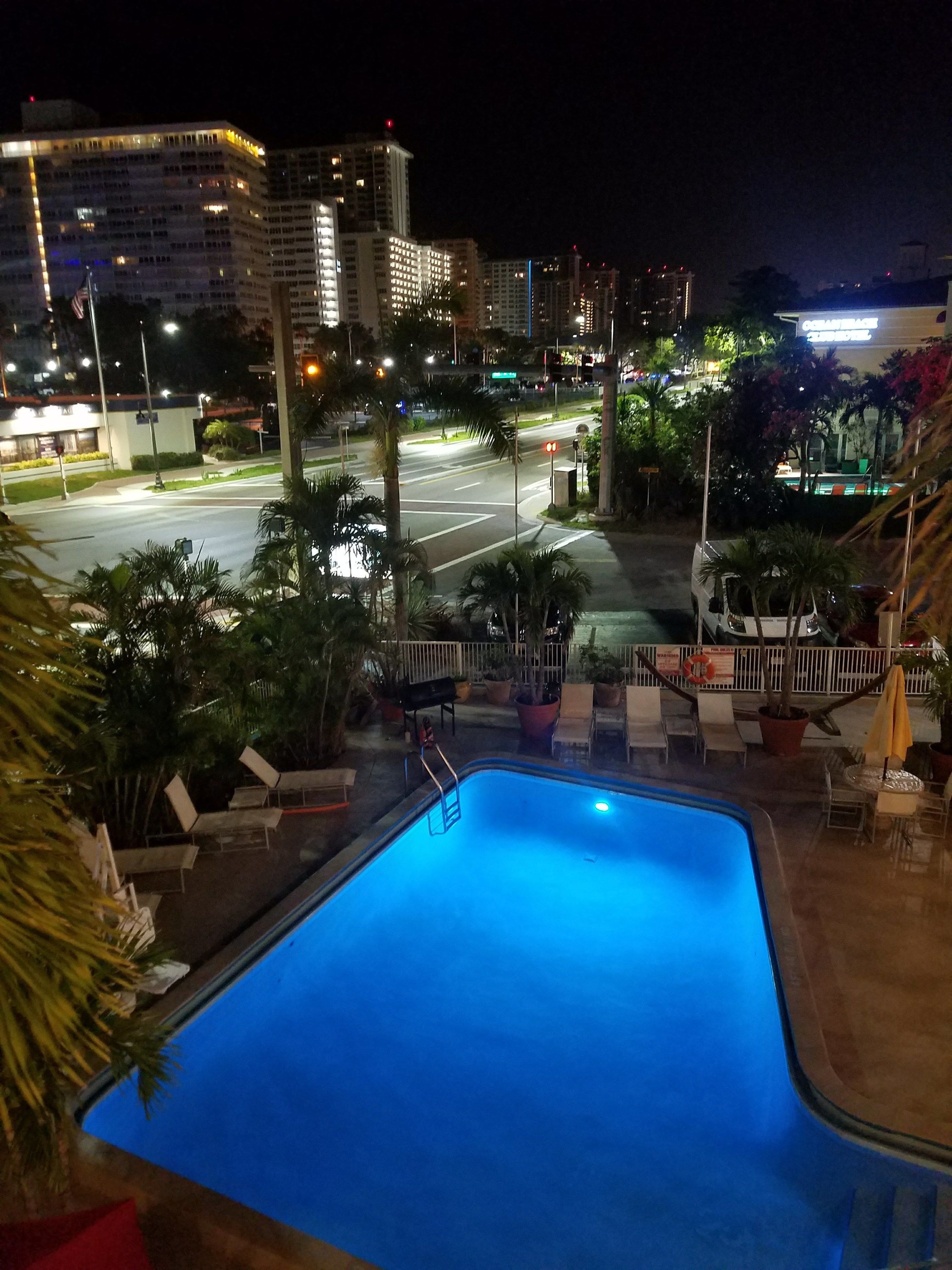 A nighttime view of a swimming pool area with a view of the cityscape in the background.