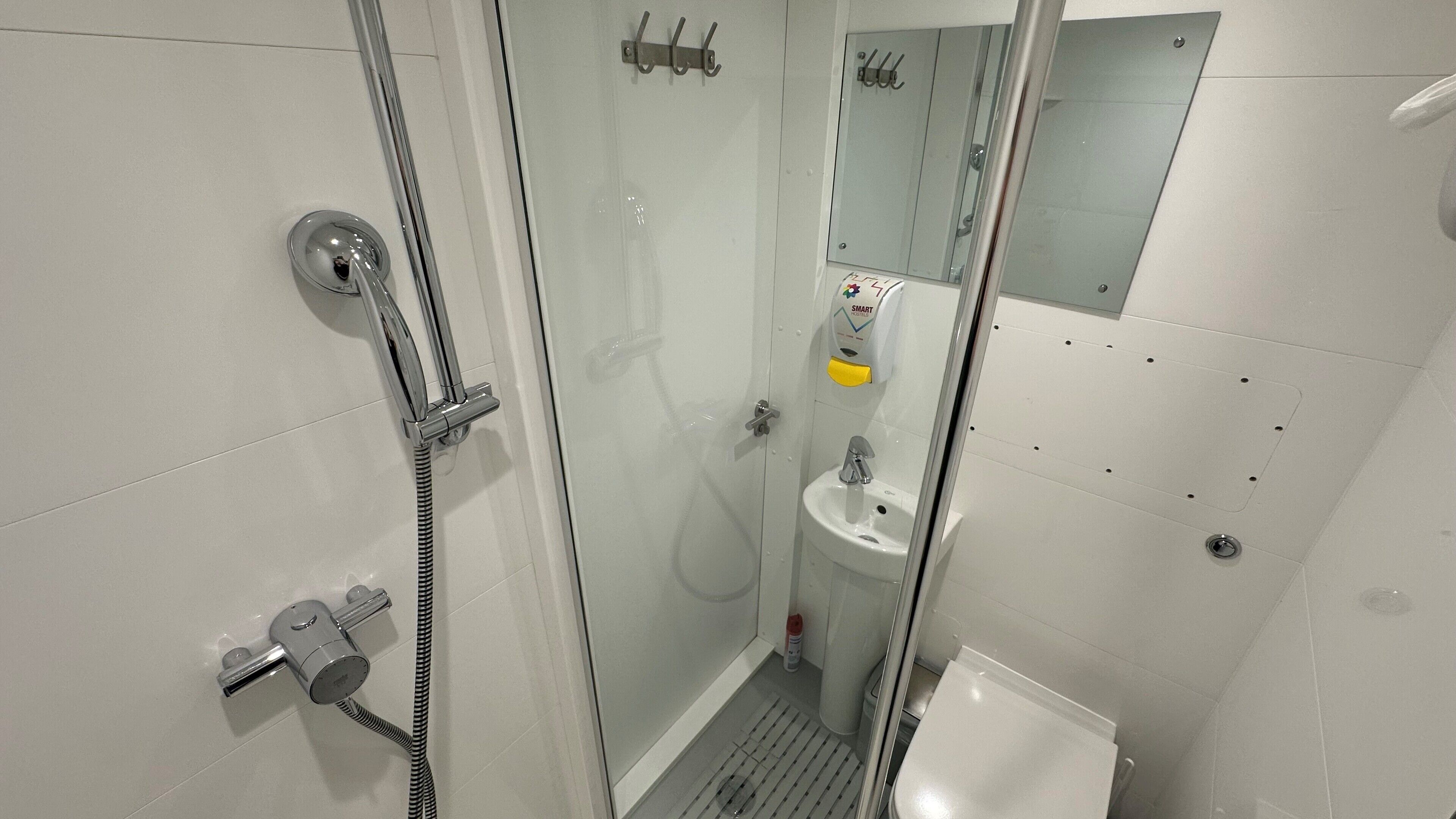 Une salle de bain moderne avec une douche à parois de verre, un lavabo blanc et un miroir.