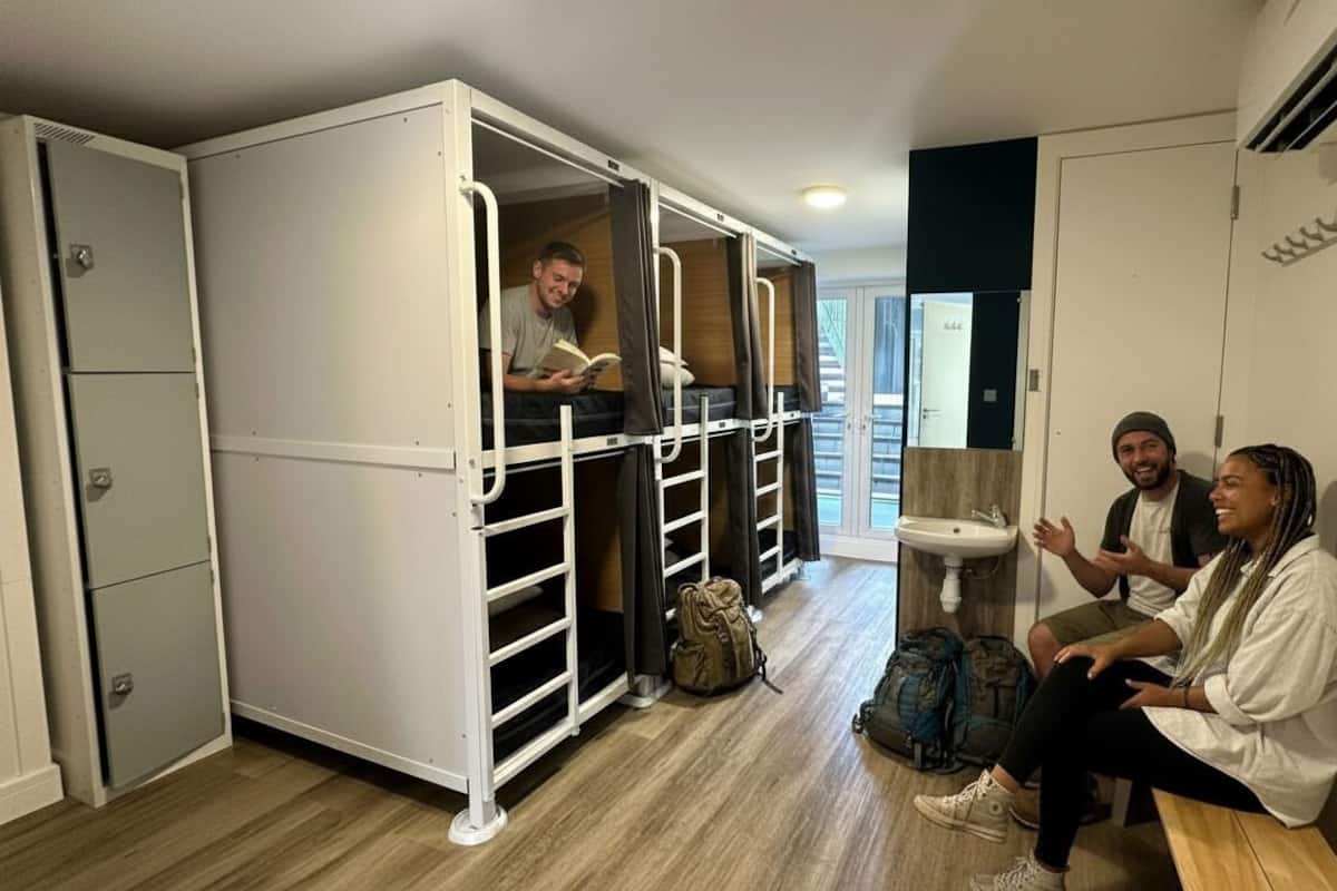 A compact room with a bunk bed, a small sink, and a bench.