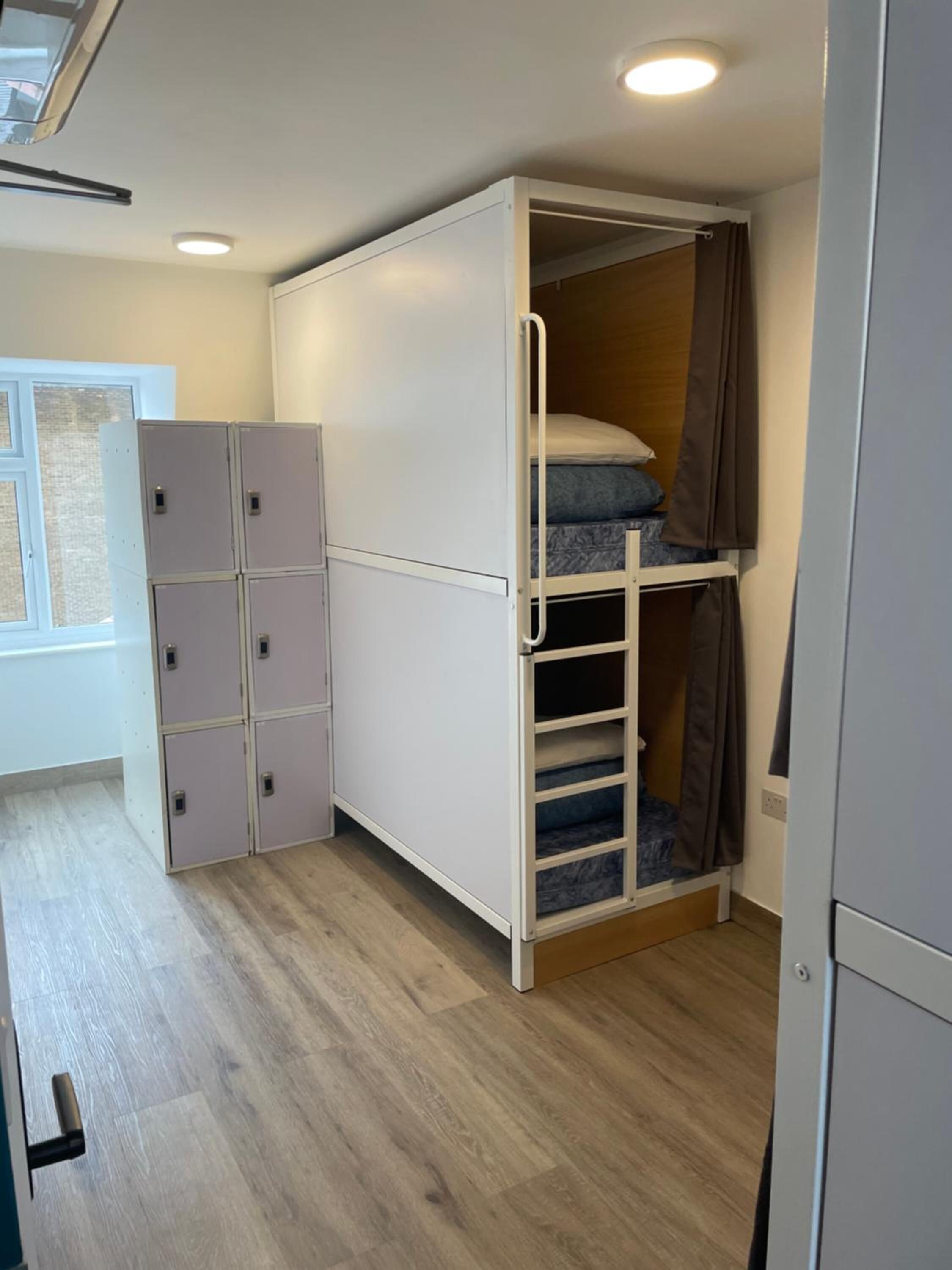 Una habitación compacta con literas, armario empotrado y ventana.