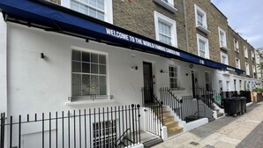 A building with a sign reading "WELCOME TO THE WORLD FAMOUS CAMDEN INN!" and a fire exit sign. - Smart Camden Inn Hostel (London)