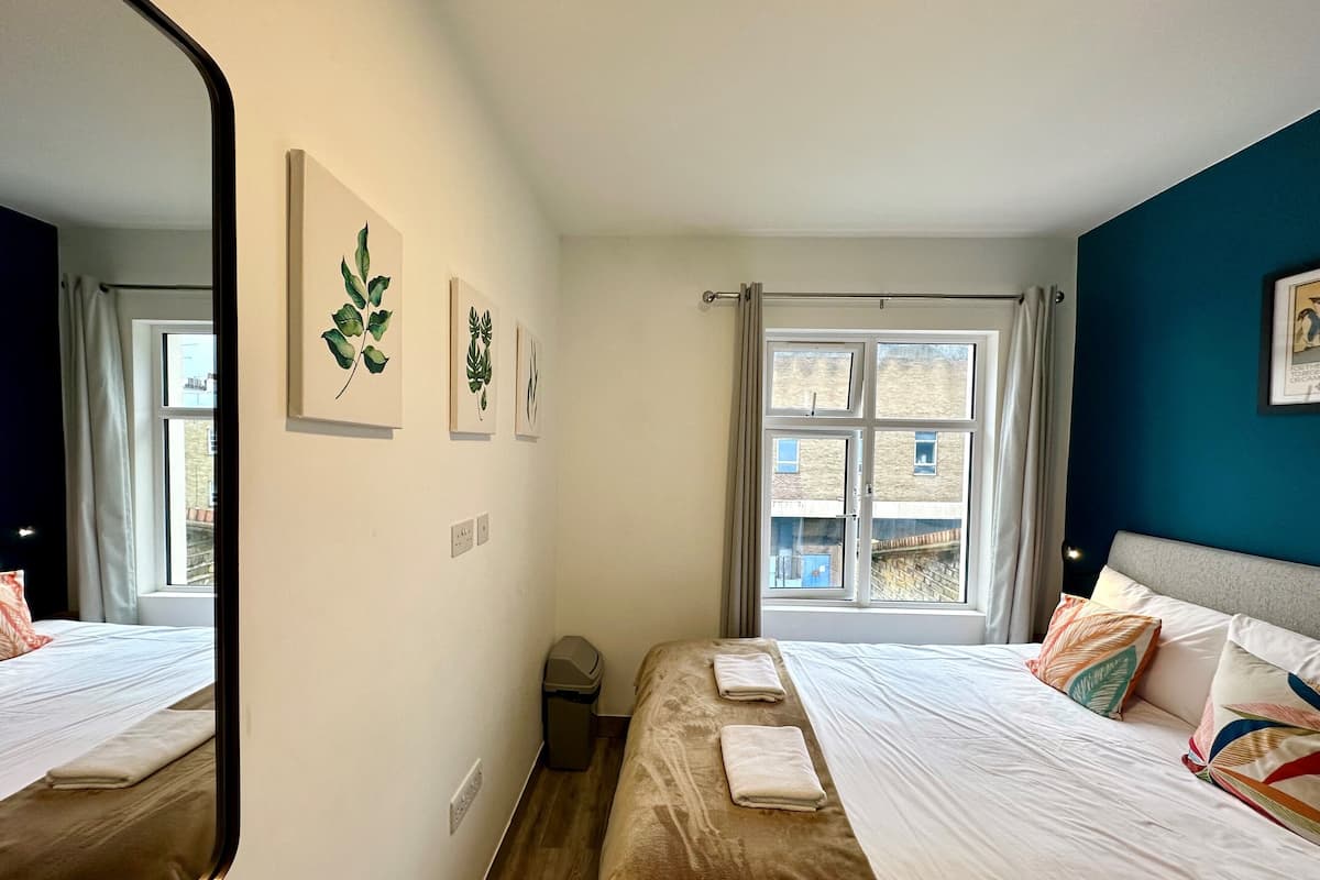 A hotel room with a bed, a window, and wall art.