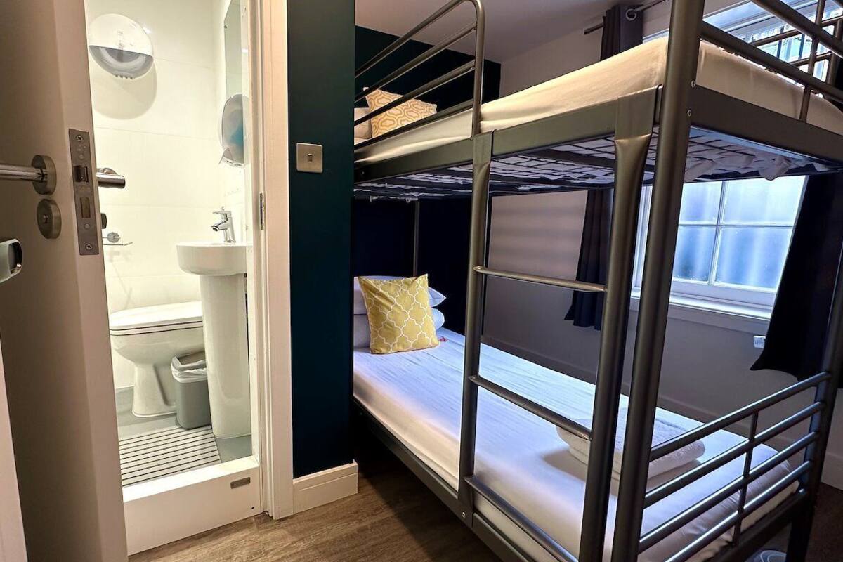 A bunk bed room with a bathroom that includes a toilet and sink.