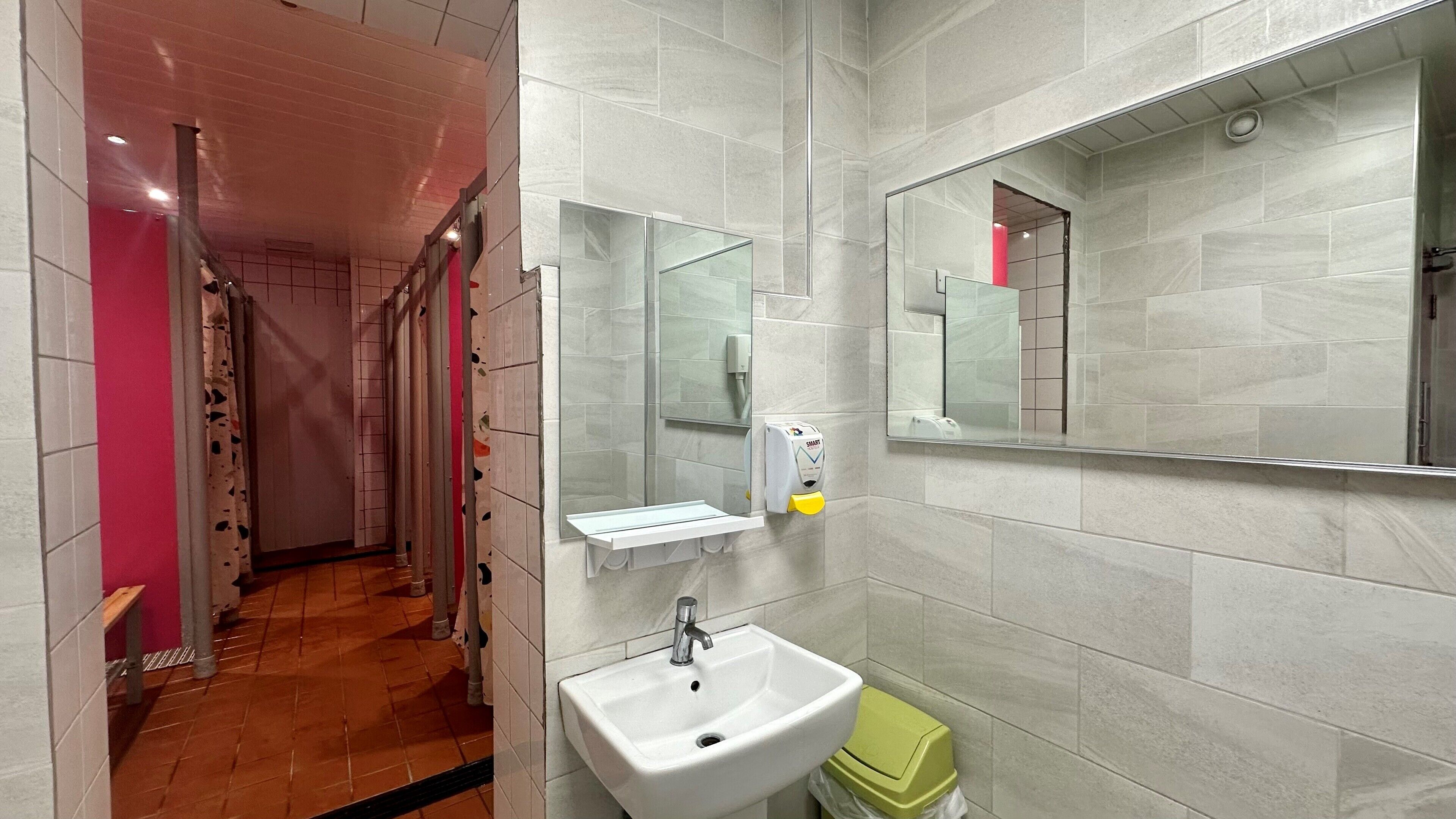 Une salle de bain moderne avec un lavabo blanc, un miroir et un sèche-mains.