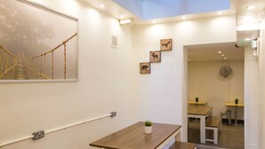 A modern interior with a wooden table, a white bench, and a mural of a rope bridge. There are three framed animal silhouettes on the wall.
