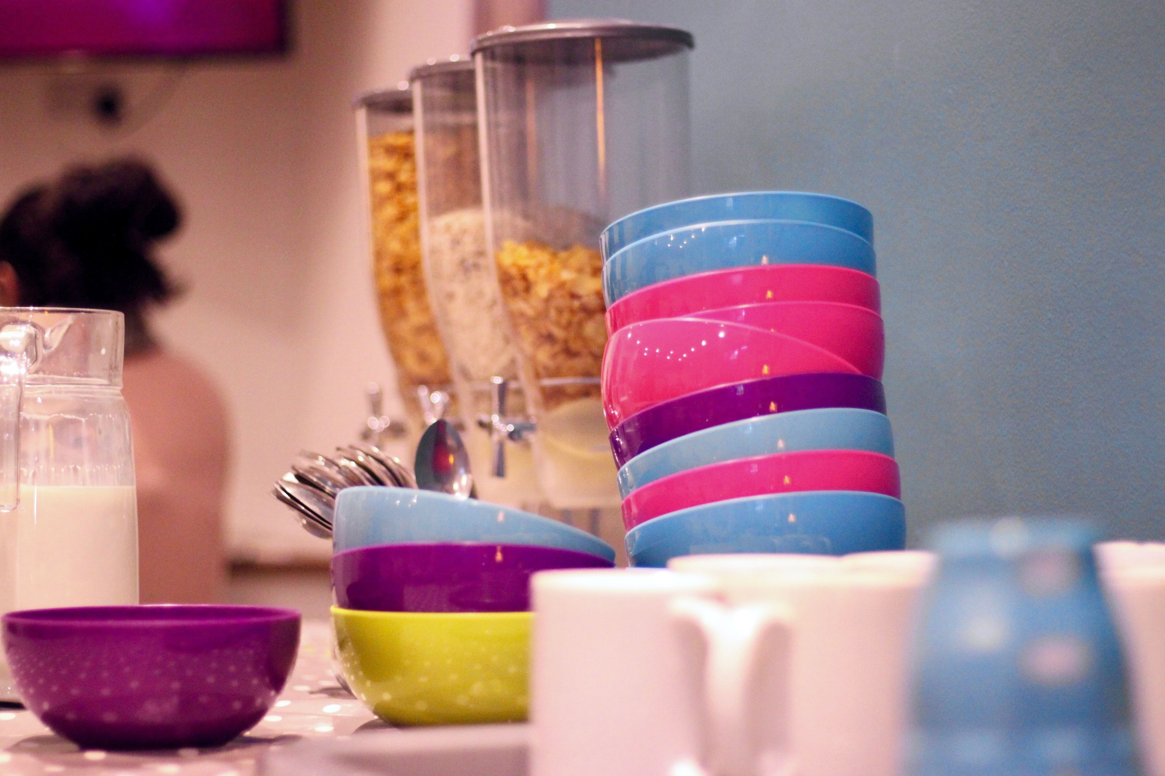 Una mesa con varias tazas de colores y un recipiente de vidrio.