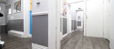 A hallway with a grey and white color scheme, wooden flooring, and a door at the end.