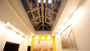 A corridor with a skylight, a framed picture of a hot air balloon, and a wall-mounted picture.