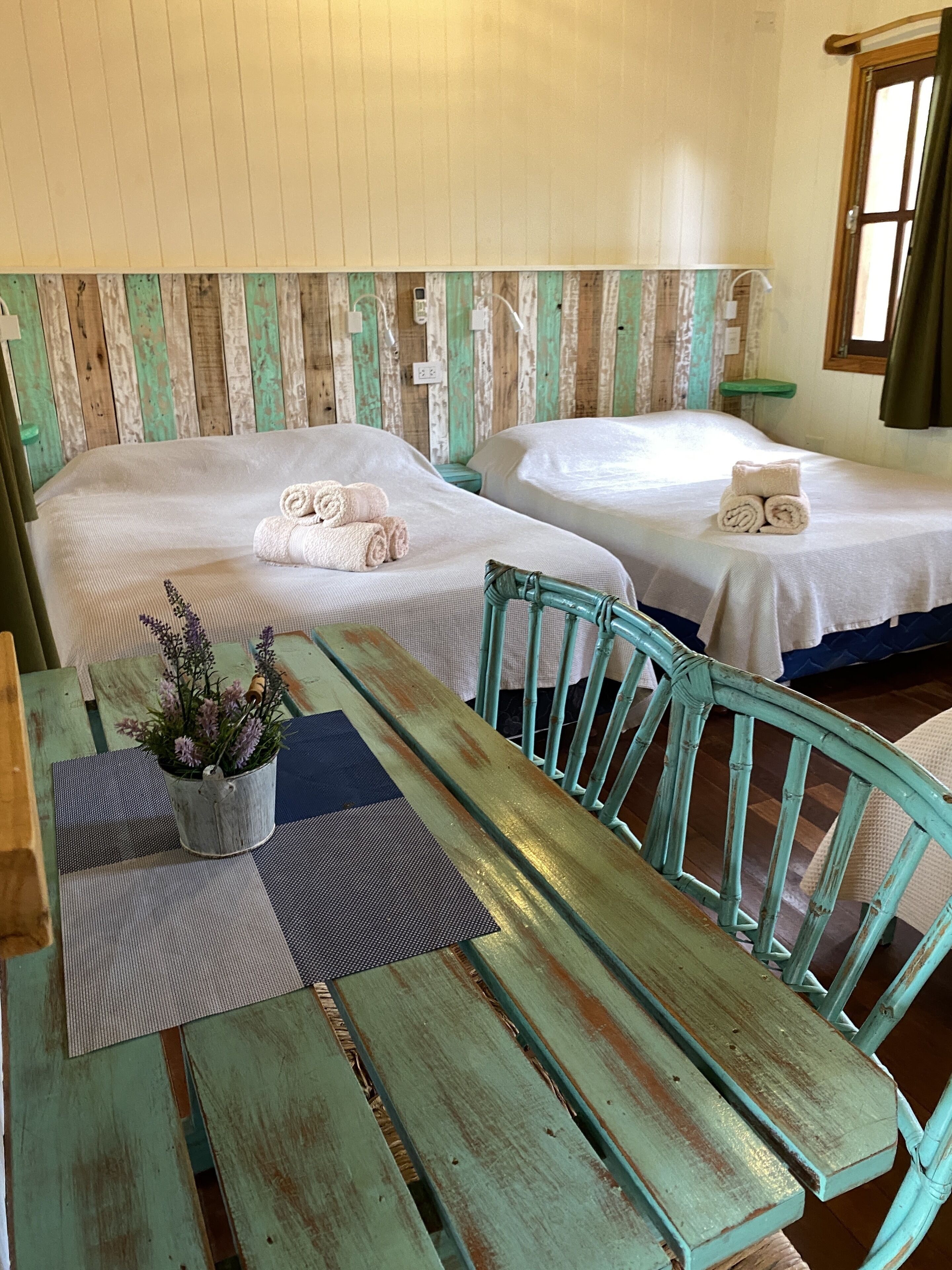 A room with two beds, a wooden table, and a bench.