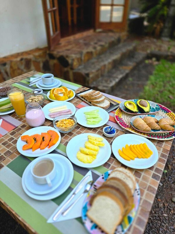 Una mesa de desayuno con diversos alimentos, como pan, frutas y bebidas.