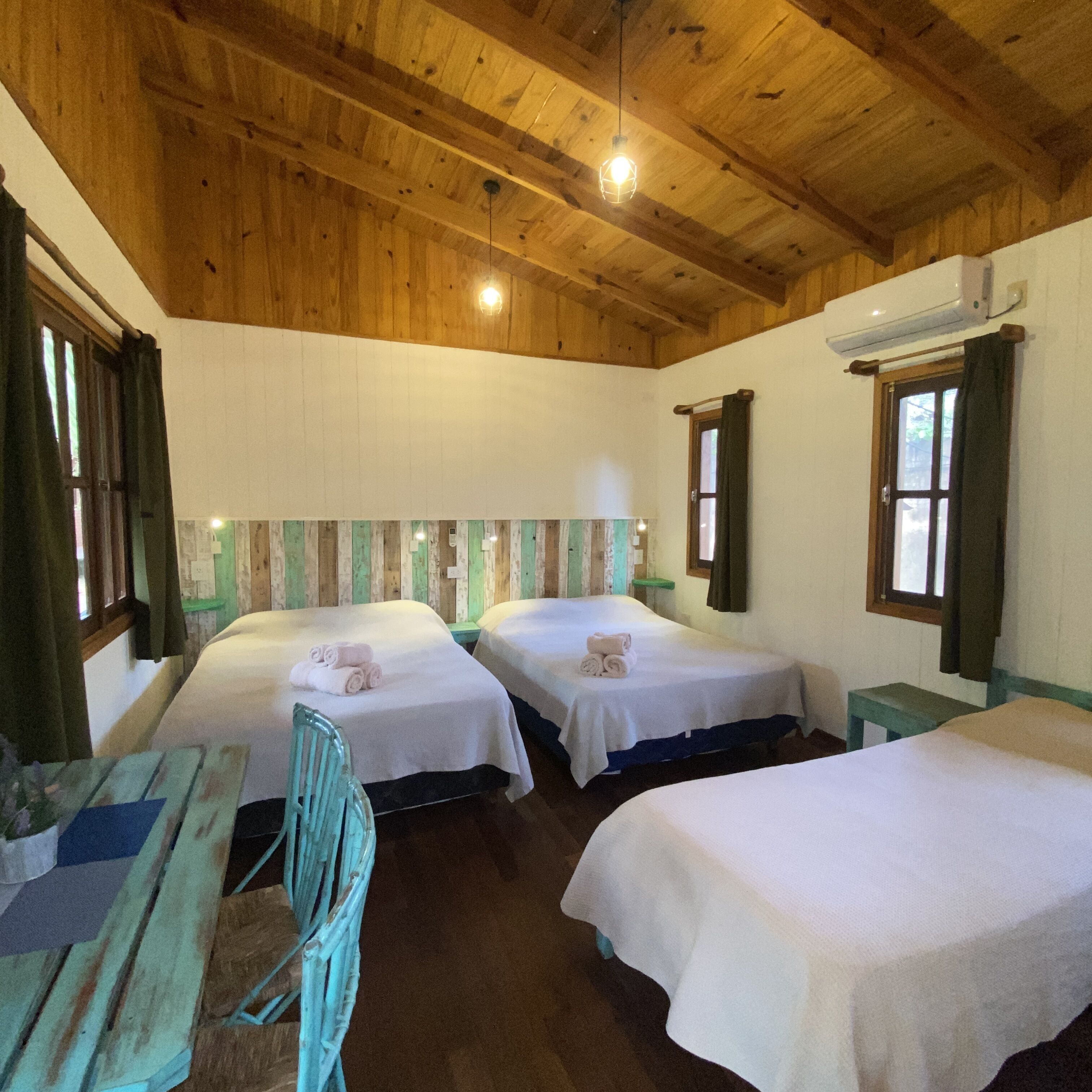 A room with two beds, wooden ceiling, and a small table with chairs.