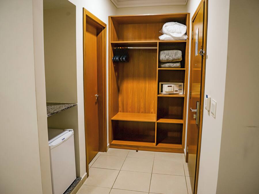 Un vestidor pequeño con estantes de madera, un calentador incorporado y un refrigerador pequeño.