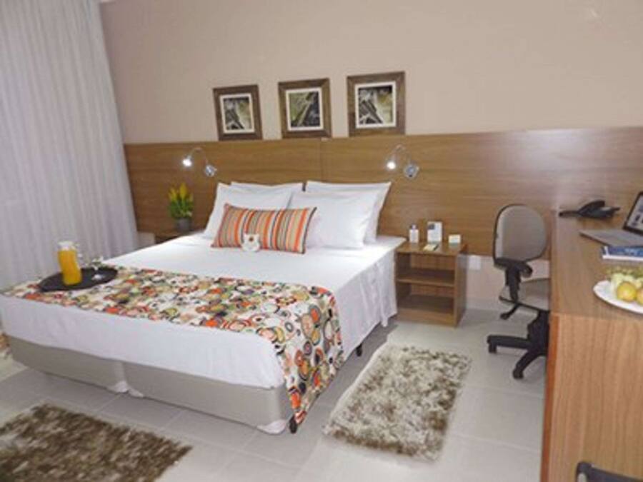 Una habitación de hotel con cama, mesita de noche, escritorio y silla.