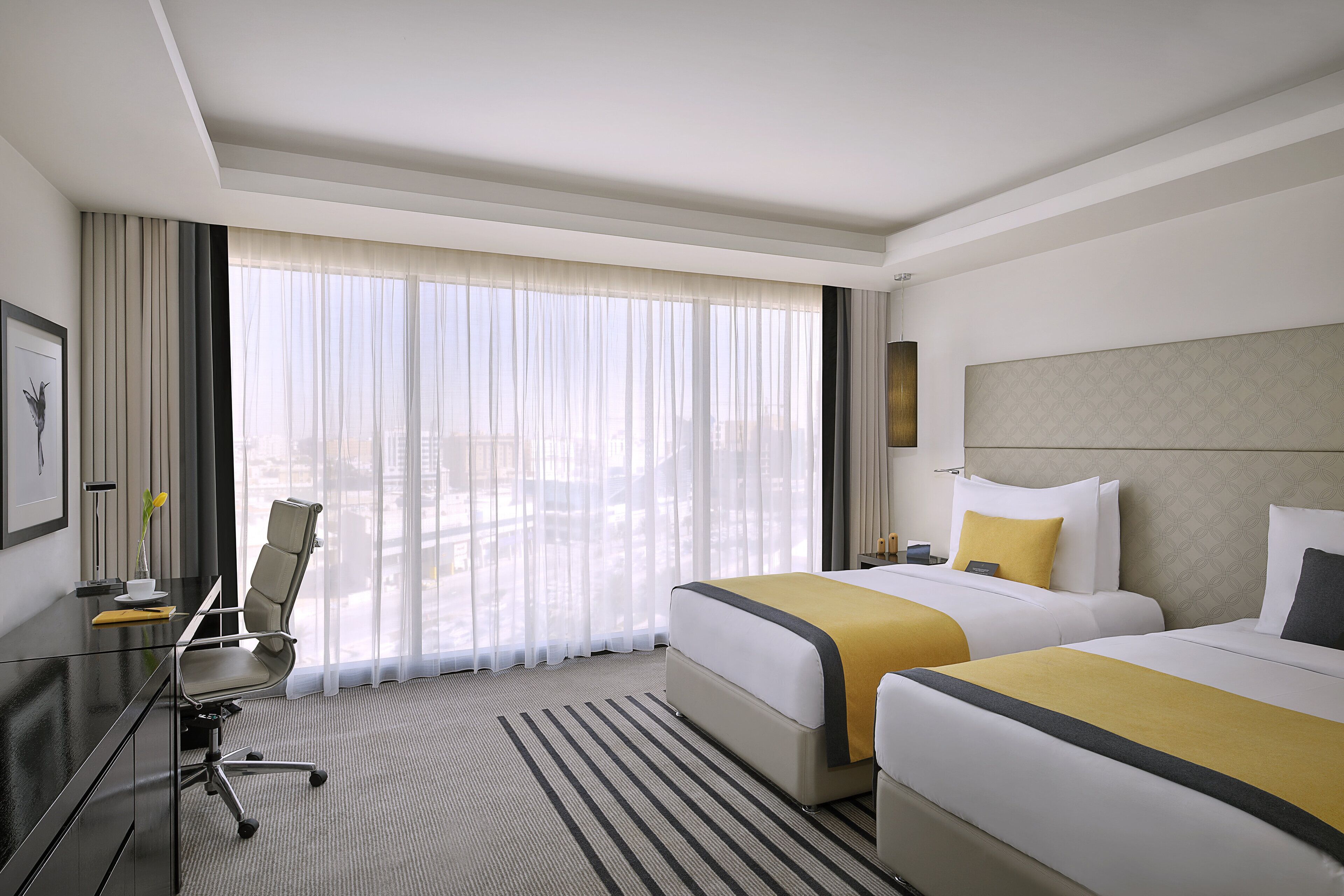 A hotel room with two beds, a desk, and a chair.