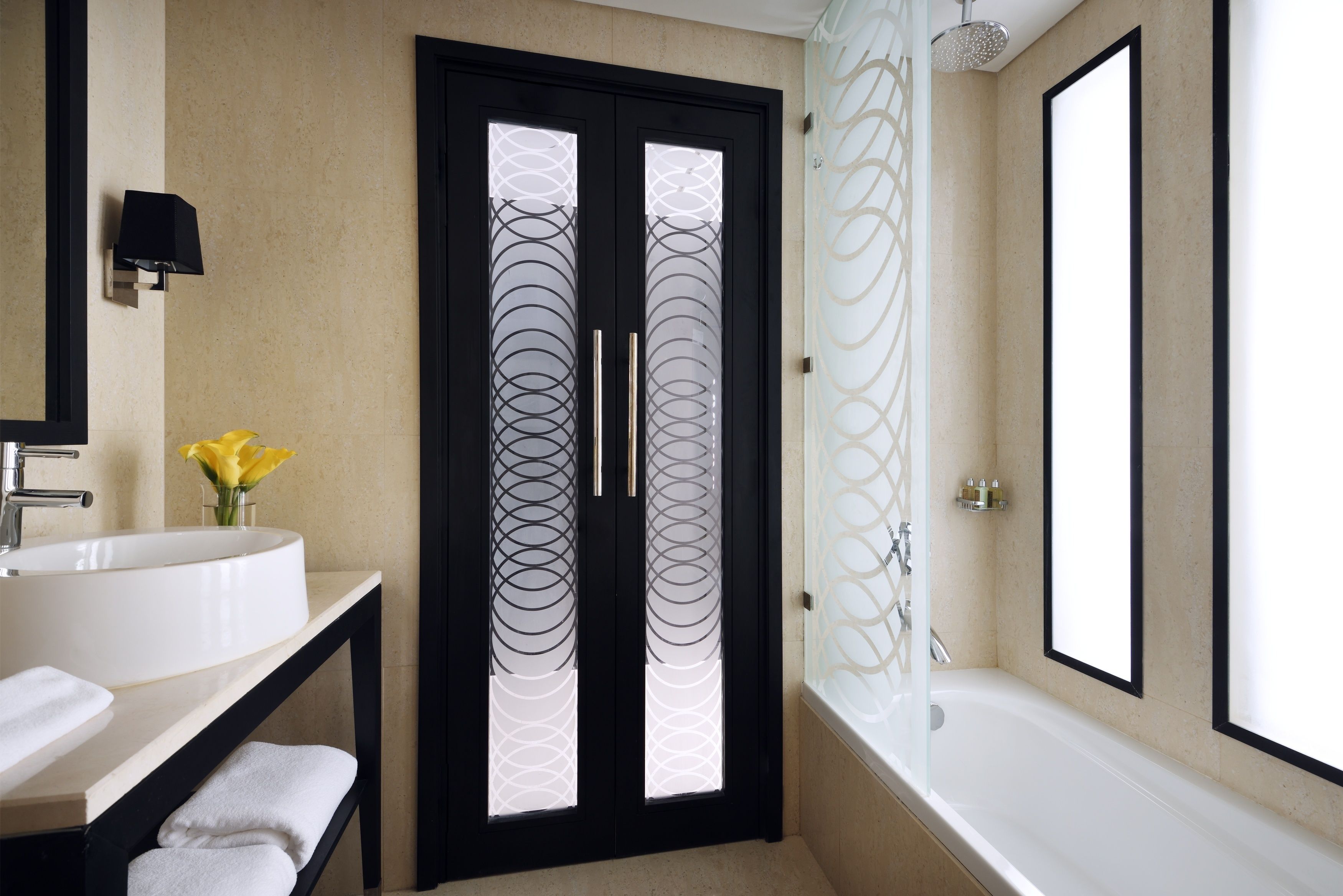A bathroom with a white sink, a black-framed mirror, a glass shower enclosure, and a bathtub.