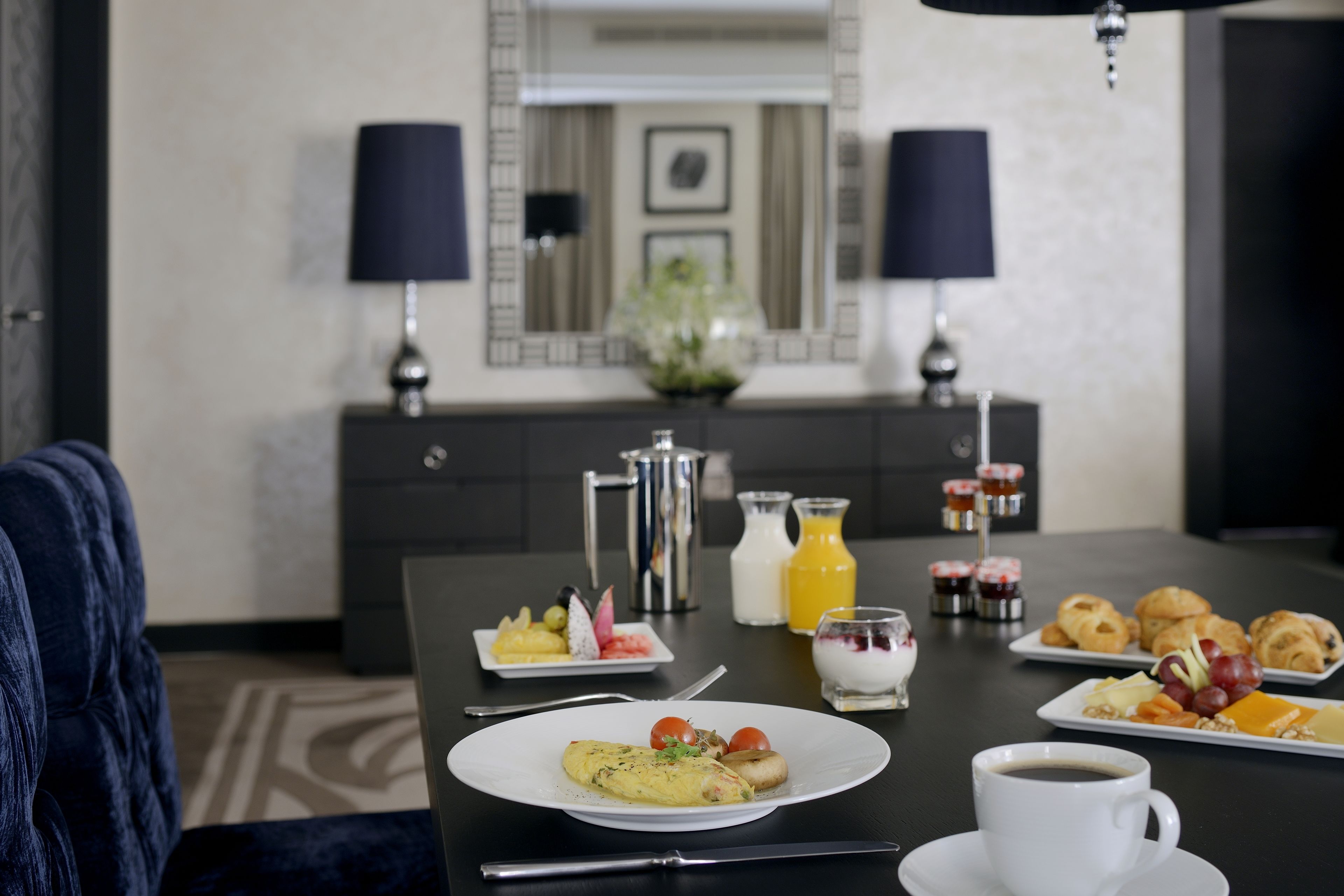 Ein Esstisch mit Frühstücksgebäck, eine Kaffeetasse und ein Sofa in einem Hotelzimmer.