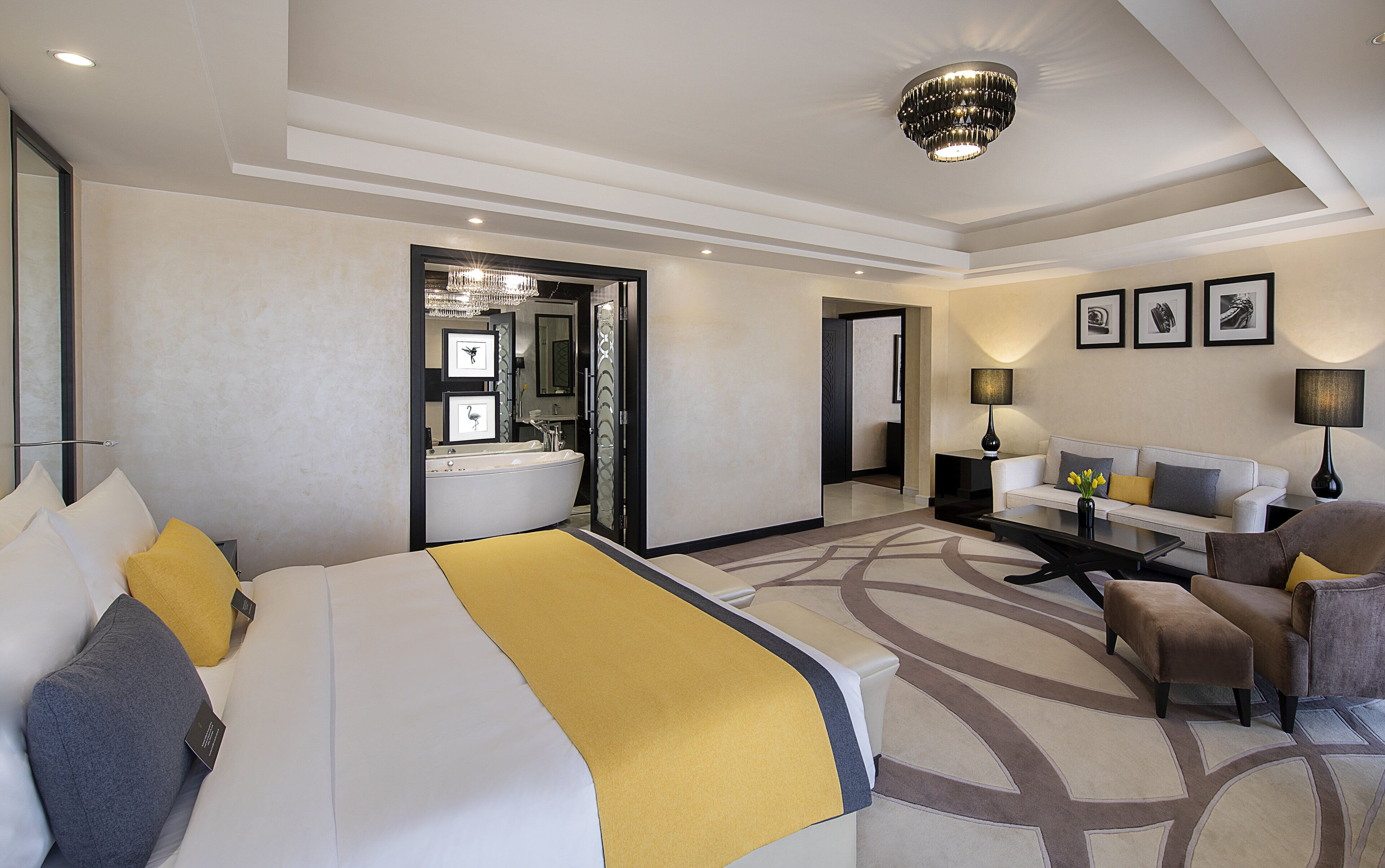 Une chambre d’hôtel dotée d’un grand lit, d’un coin salon avec un canapé et des fauteuils, d’un bureau, ainsi que d’une salle de bain avec une baignoire et un miroir.