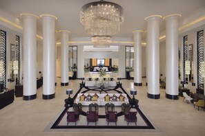 A spacious lobby with a central seating area, large columns, and a chandelier.