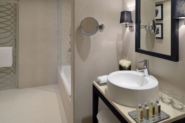 A modern bathroom with a large sink, mirror, and glass shower enclosure.