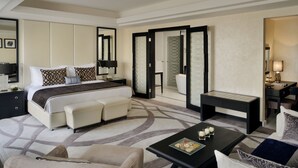 A modern hotel room with a large bed, a sofa, a coffee table, and a desk.
