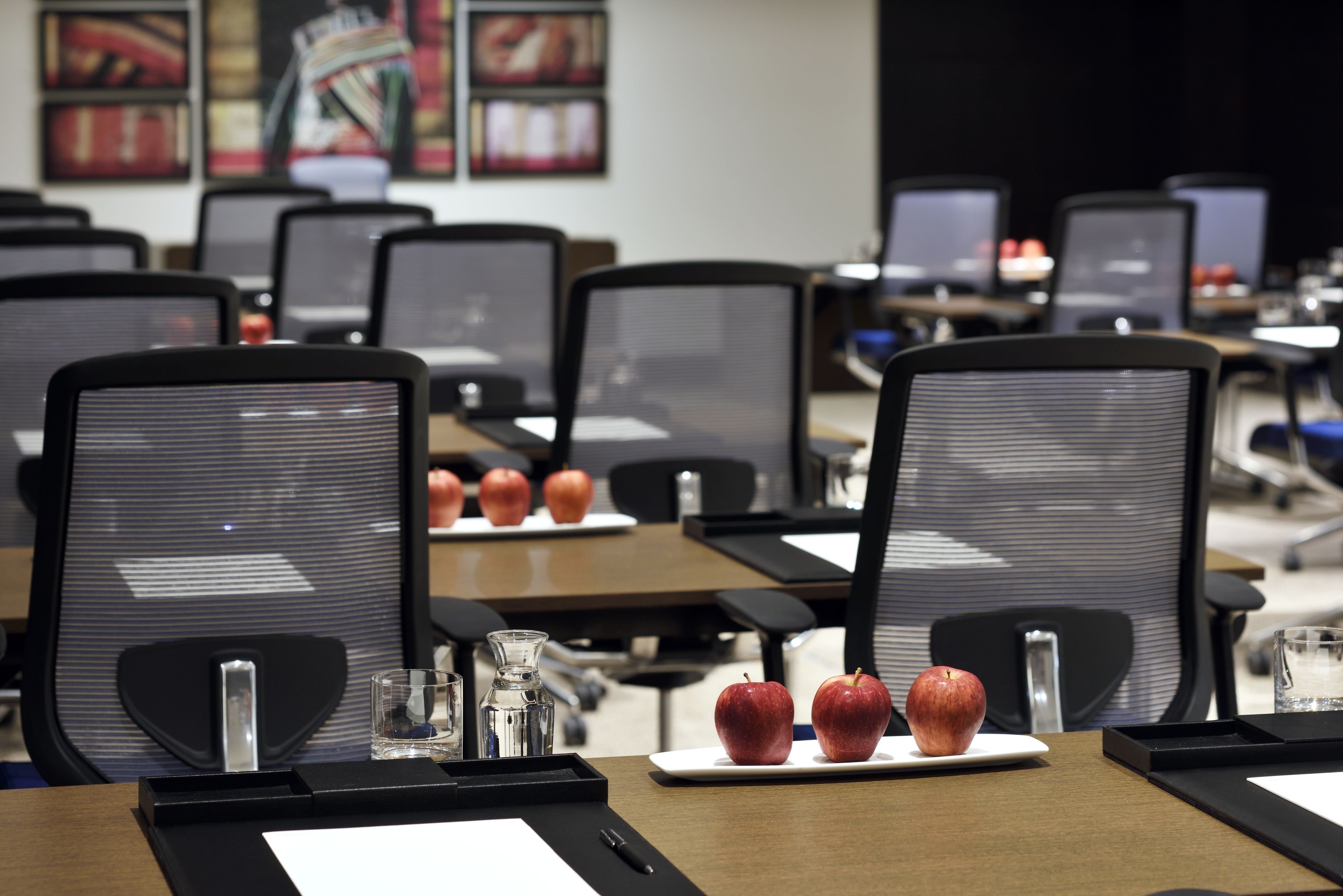 A conference room with rows of chairs, tables, and laptops.