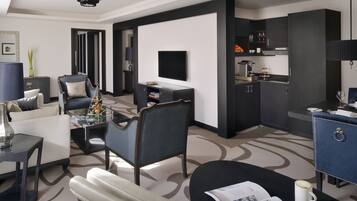 Een moderne hotelkamer met een zithoek, een eettafel, een bank, een televisie en een kitchenette.