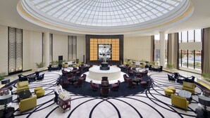 A spacious lobby with a central fountain, a high ceiling with a skylight, and a circular seating arrangement.