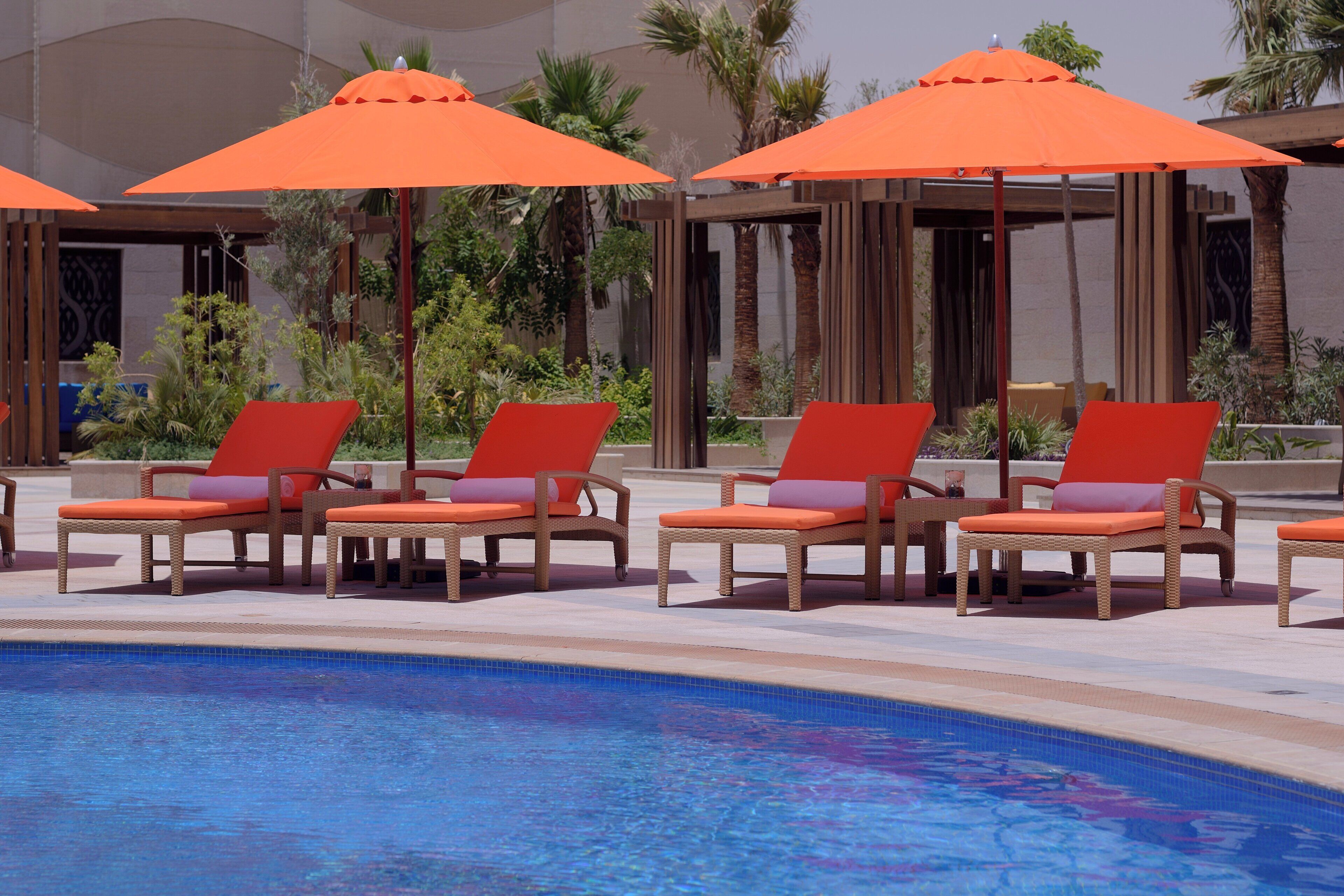 Un área junto a la piscina con sillas de descanso y sombrillas.
