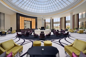 A spacious lobby with a high ceiling and a central seating area, featuring multiple sofas and chairs, a reception desk, and large windows providing natural light. - voco Riyadh by IHG (Riyadh)