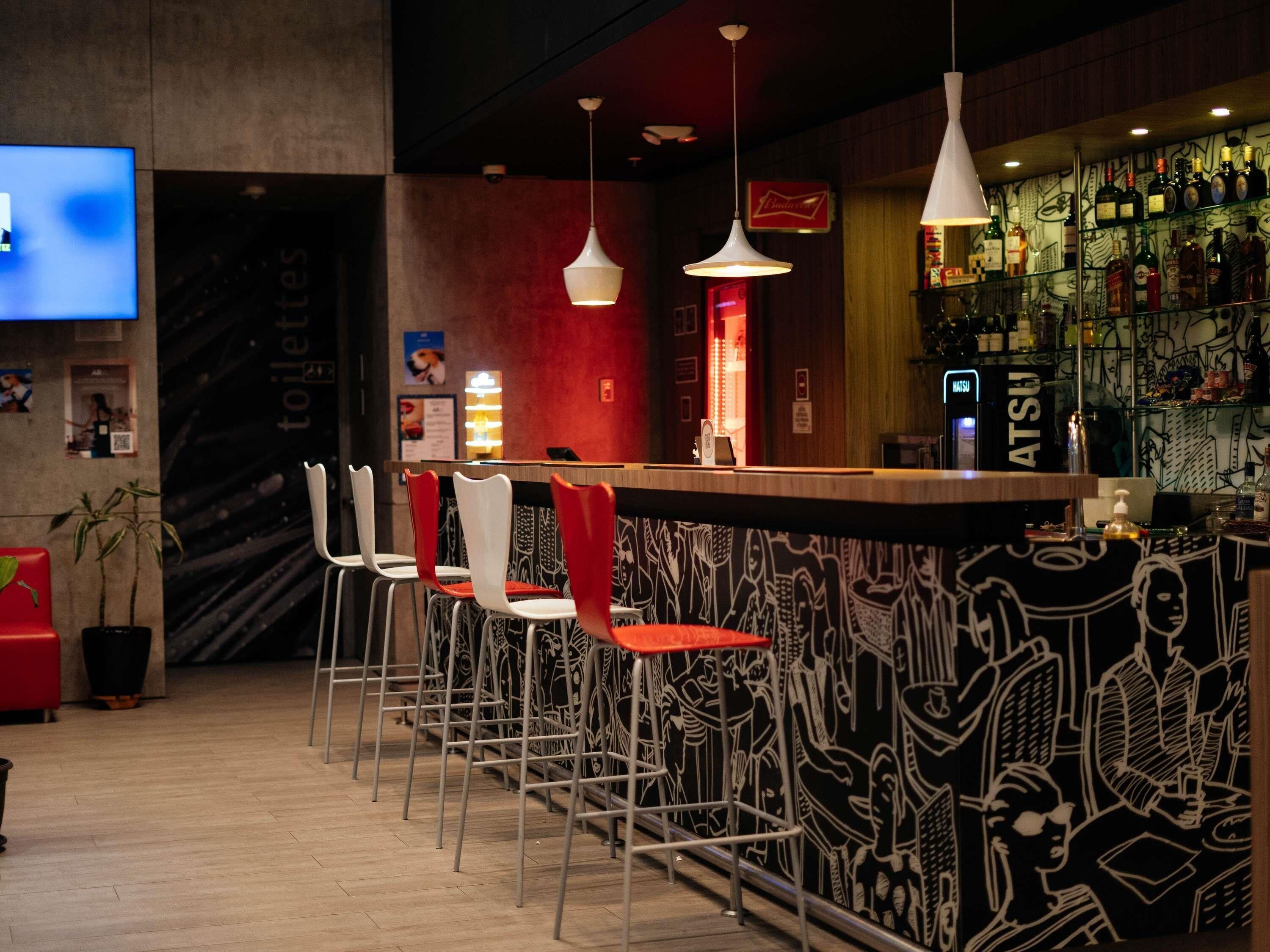 A bar area with a counter, bar stools, and a wall with a black and white mural.
