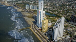 Un paysage urbain côtier avec de hauts immeubles, une plage et une route qui longe le rivage.