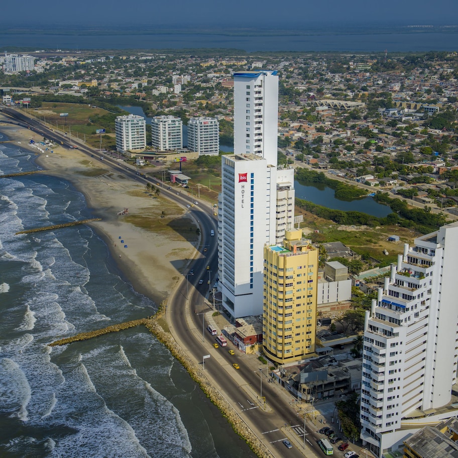A coastal cityscape with high-rise buildings, a beach, and a road running parallel to the shore.
