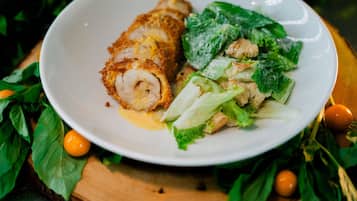 A plate with a rolled meat dish and a salad with croutons.