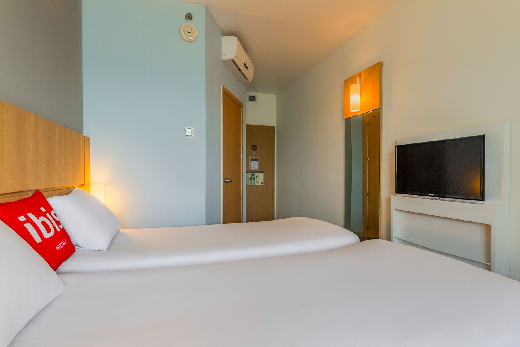 Una habitación de hotel con cama, televisión y puerta que da a un baño.