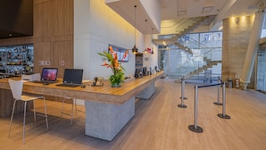 Un espace d’accueil moderne avec un comptoir de réception en bois, deux ordinateurs portables, un téléphone et une plante décorative.