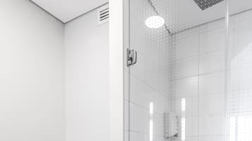 A modern bathroom with a toilet, a glass-enclosed shower, and a tiled floor.