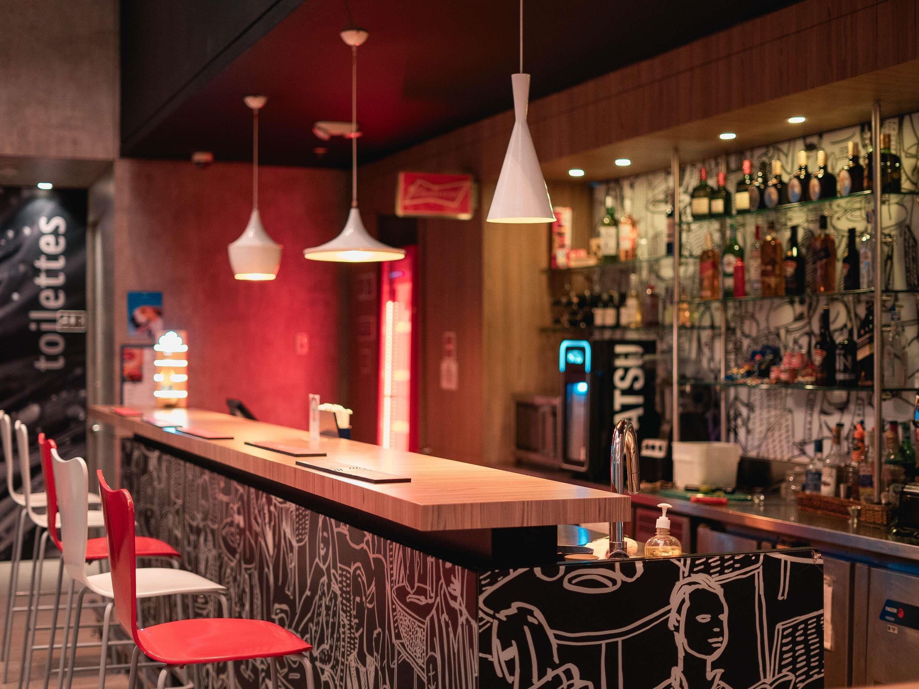 Zona de bar con mostrador, luces colgantes y pared con diseño de grafiti.