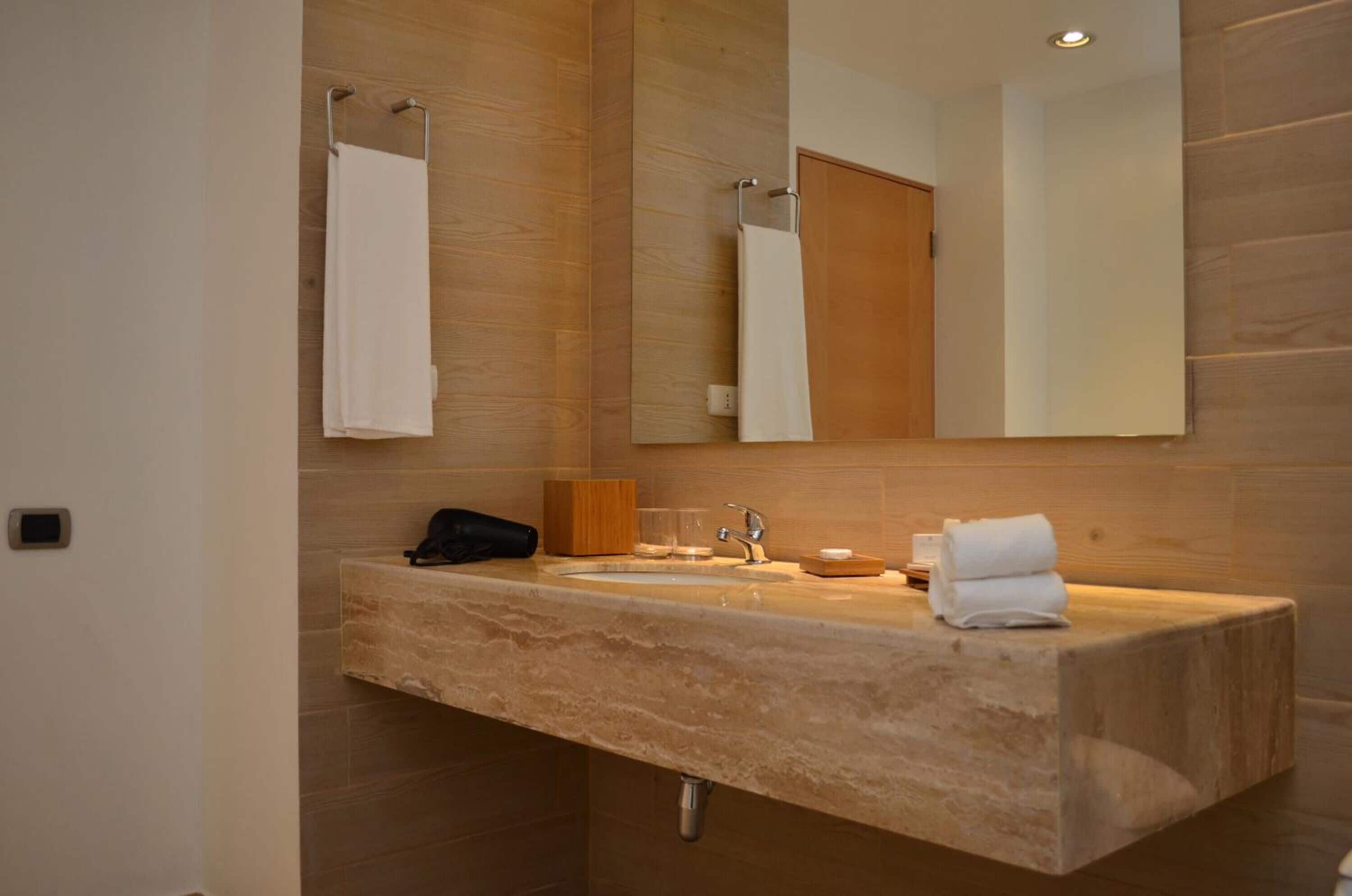 Un baño moderno con lavamanos de mármol, un espejo y un perchero para toallas.
