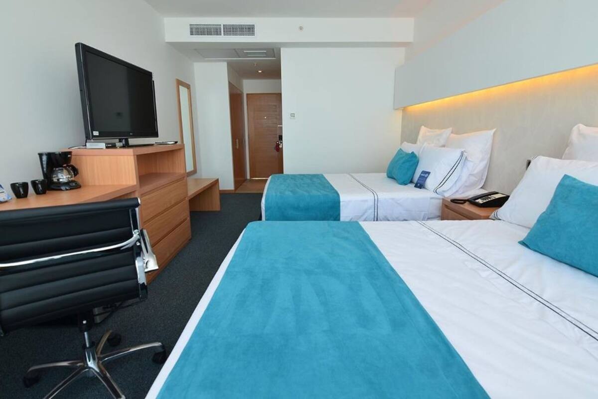 Une chambre d’hôtel avec deux lits, un bureau avec une télévision et une machine à café.